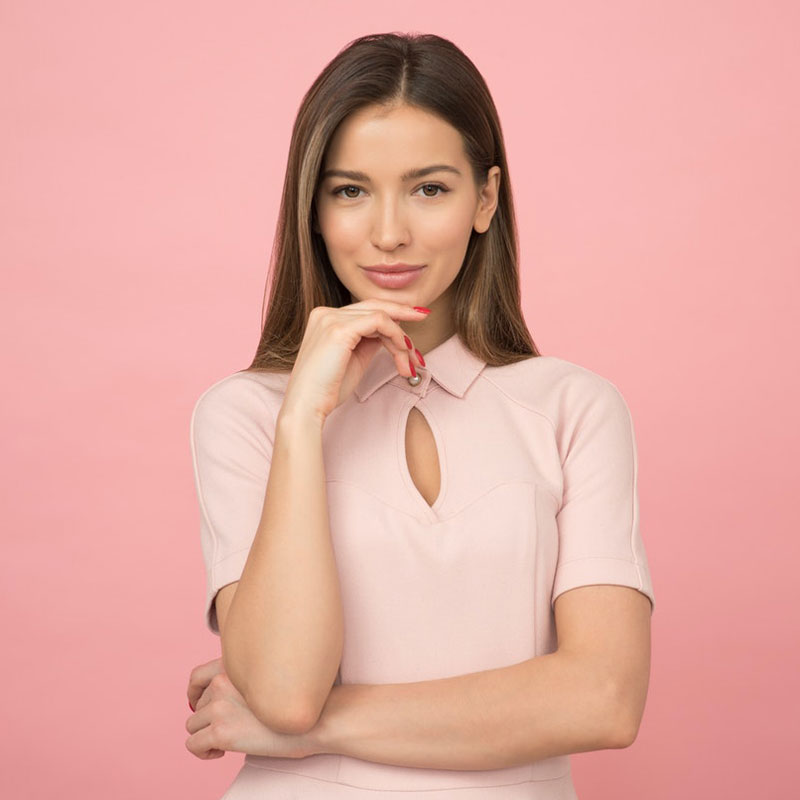 Woman wearing pink collared half sleeved top and touching her chin