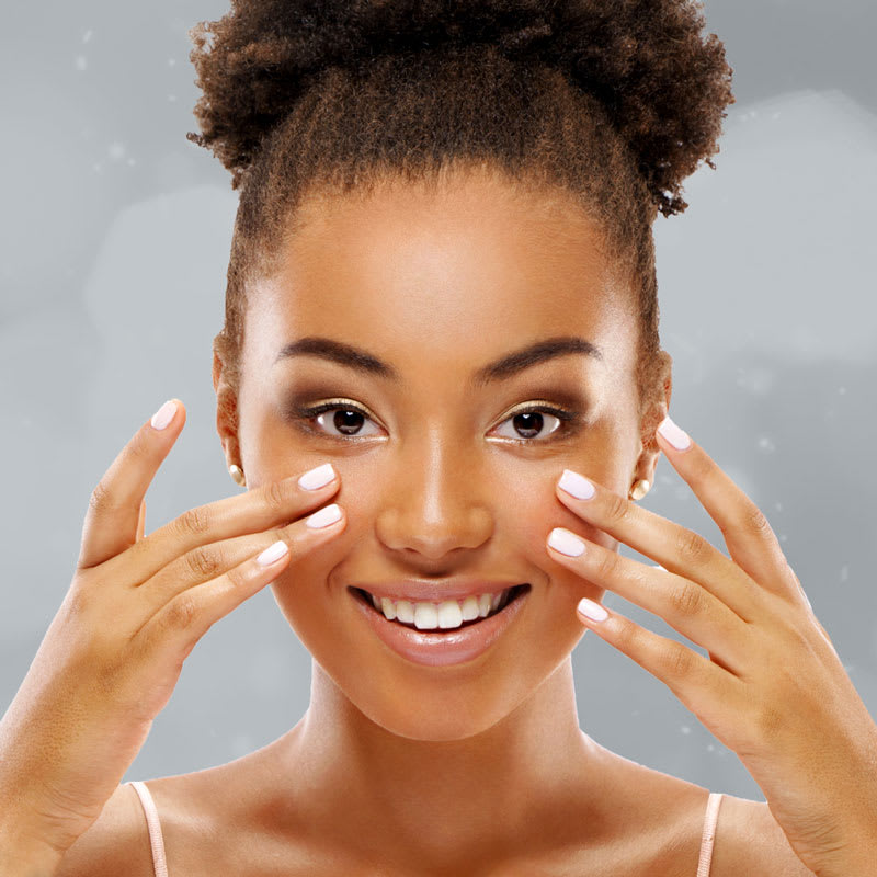 Young woman of color smiling and touching her cheeks